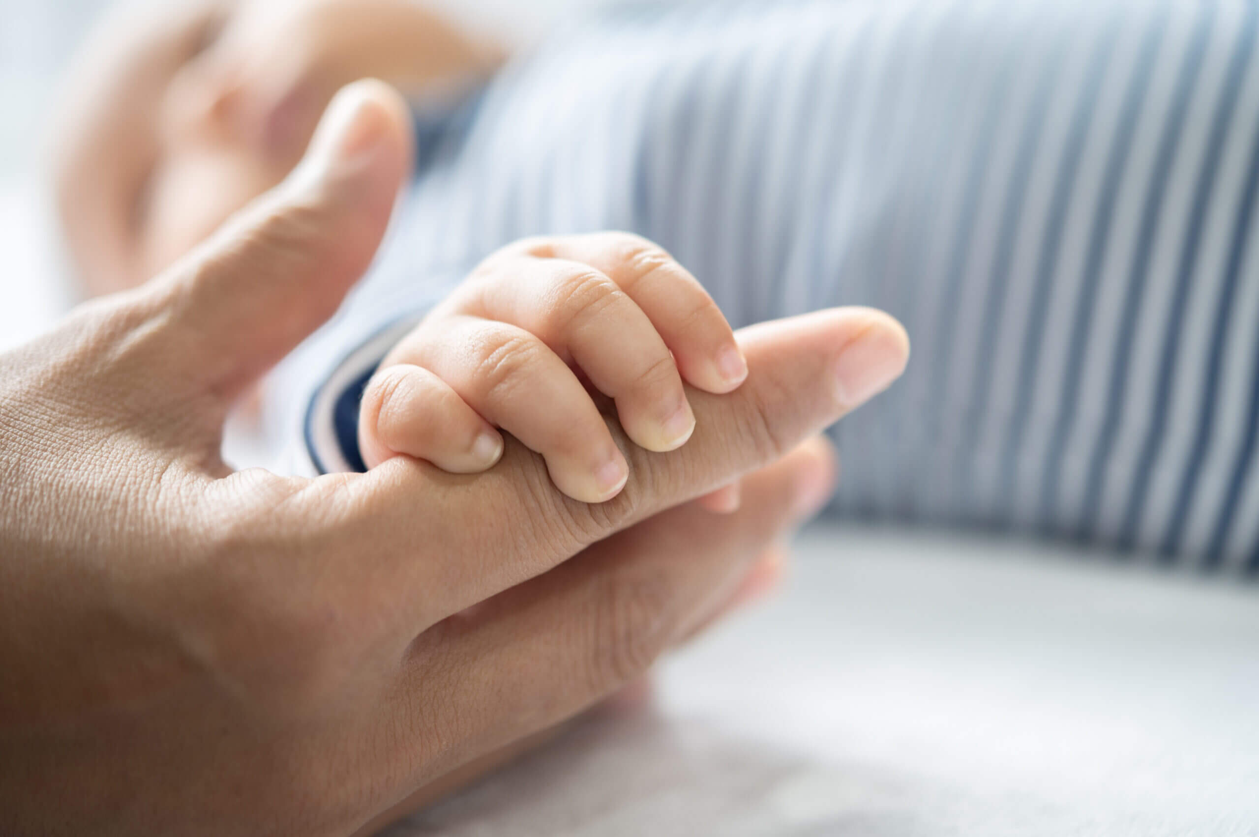 Young child holding mother’s hand, symbolizing family and guidance
